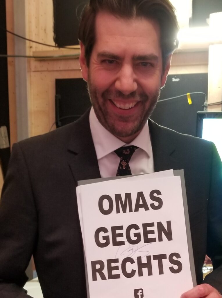 Klaus von Wagner signiert ein Plakat der OMAS